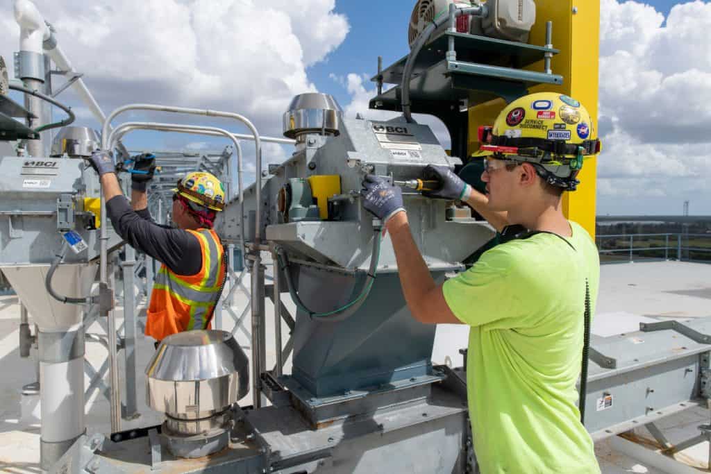 Workers inspecting industrial machinery on rooftop.