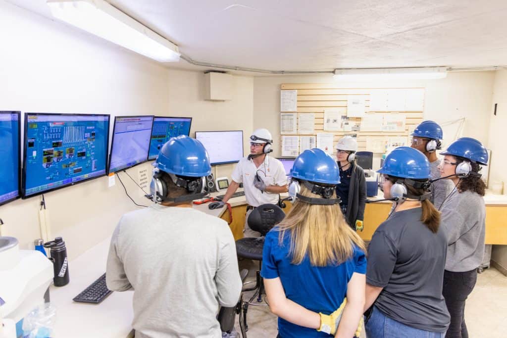 Workers in control room monitoring screens.
